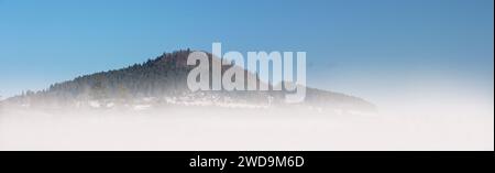 Au soleil de midi, la majestueuse montagne Lupfen, le plus haut sommet de la région de Baar, s'élève lentement au-dessus du doux brouillard de la vallée. Banque D'Images