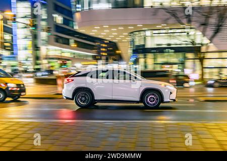 Innerstädtische Straße mit Fahrzeugen, moderne Architektur am Abend. Bewegungsunschärfe. SUV. // 17.01.2024 : Stuttgart, Bade-Württemberg, Deutschland. *** Rue intérieure avec des véhicules, architecture moderne dans le soir Motion Blur SUV 17 01 2024 Stuttgart, Baden Württemberg, Allemagne Banque D'Images