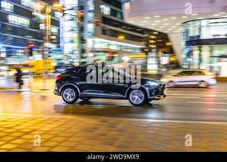 Innerstädtische Straße mit Fahrzeugen, moderne Architektur am Abend. Bewegungsunschärfe. SUV. // 17.01.2024 : Stuttgart, Bade-Württemberg, Deutschland. *** Rue intérieure avec des véhicules, architecture moderne dans le soir Motion Blur SUV 17 01 2024 Stuttgart, Baden Württemberg, Allemagne Banque D'Images