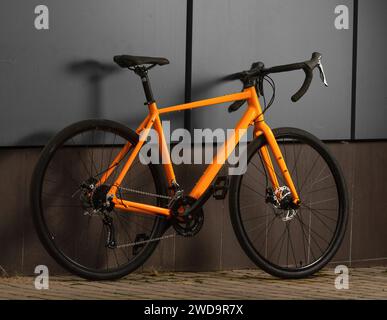 Bicyclette en gravier. Vélo orange brillant pour le cyclisme tout-terrain sur fond gris. Gros plan. Vue latérale. Banque D'Images