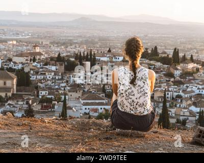 Jeune belle femme caucasienne voyageur solo regardant le coucher du soleil à Grenade, Andalousie, Espagne, heure d'or, bâtiments blancs, paysage urbain, adven Banque D'Images