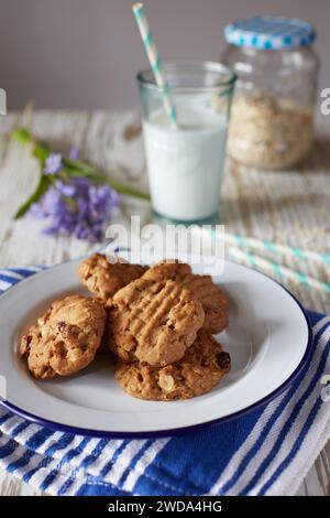 Biscuits muesli faits maison avec avoine et raisins secs sur assiette, verre de lait en arrière-plan, concept de snack sain. Banque D'Images