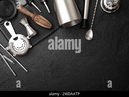 Shaker à cocktail en acier, passoire, jigger et presse-agrumes en bois avec muddler sur plateau en caoutchouc avec cuillère et paille argentée. Banque D'Images