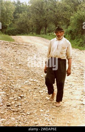 Comté de Vrancea, Roumanie, 1990. Homme local marchant pieds nus sur un chemin rocheux. Banque D'Images