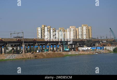 Ahmedabad, Gujarat, Inde. 13 janvier 2024. Un train passe sur le pont à côté du chantier de construction au milieu du salon commercial mondial Gujarat animé à Ahmedabad. Vibrant Gujarat Global Trade Show est une plate-forme pour amener les investisseurs indiens et internationaux à investir dans l'État, créant ainsi des opportunités d'affaires et d'emploi pour des milliers de personnes et renforçant l'économie. (Image de crédit : © Ashish Vaishnav/SOPA Images via ZUMA Press Wire) USAGE ÉDITORIAL SEULEMENT! Non destiné à UN USAGE commercial ! Banque D'Images