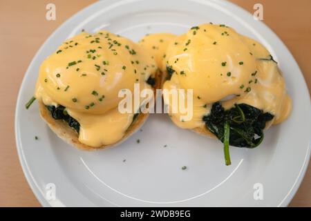 La sauce hollindaise jaune sur le dessus de deux œufs pochés qui sont sur un lit d'épinards sur des muffins anglais grillés. Le plat est appelé Egg Florenitne. Banque D'Images