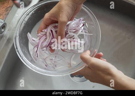 laver les oignons hachés avec de l'eau dans un bol, la préparation d'aliments sains, les légumes frais, les détails des travaux ménagers Banque D'Images