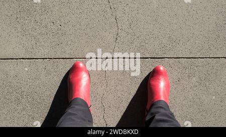 Femme portant des bottes rouges, vue d'en haut, sur le point de franchir une ligne Banque D'Images