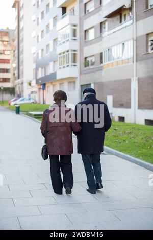 Un couple âgé de plus de 70 ans vu de l'arrière se balader dans une rue vide par une journée ensoleillée. Concept social distance Covid 19 Banque D'Images