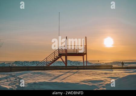 Tour de sauveteur avec en toile de fond le coucher du soleil sur une plage enneigée à Parnu, Estonie Banque D'Images