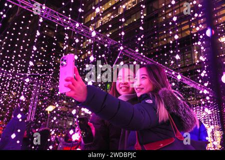 Londres, Royaume-Uni. 19 janvier 2024. Deux visiteurs prennent des photos de « Submergence » de Squidsoup (Royaume-Uni) à Montgomery Square, qui est de retour à la demande populaire après son succès aux Winter Lights en 20219. Les « Winter Lights » annuelles sont spectaculaires et permettent de voir gratuitement des installations lumineuses et de l'art immersif autour de Canary Wharf dans l'est de Londres. Crédit : Imageplotter/Alamy Live News Banque D'Images