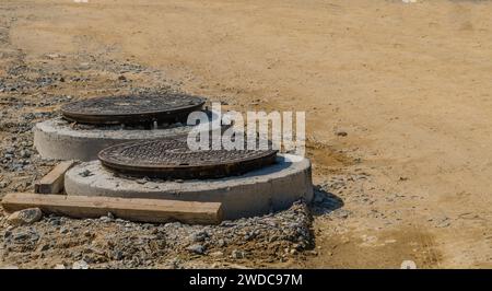 Deux couvercles de trous d'homme en acier sur de nouveaux trous d'homme en béton sur un nouveau site de construction rural, Corée du Sud, Corée du Sud Banque D'Images