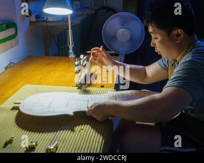 Maître luthier fabricant d'instruments à cordes procède au travail de graduation en cours de plaque arrière violoncelle, en utilisant des plans, calibre de jauge d'épaisseur Banque D'Images