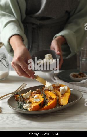 Femme mettant du fromage sur des tranches de citrouille cuites à table, gros plan Banque D'Images