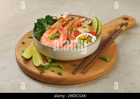 Délicieux ramen avec crevettes, œuf dans un bol et baguettes sur une table légèrement texturée. Soupe de nouilles Banque D'Images