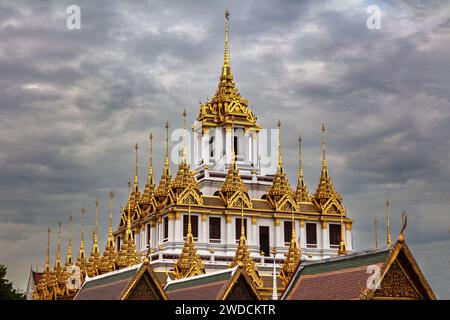 Temple en métal (Wat Ratchanatdaram) à Bangkok, Thaïlande. Flèches métalliques sur le toit. Ciel nuageux sombre au-dessus de nous Banque D'Images