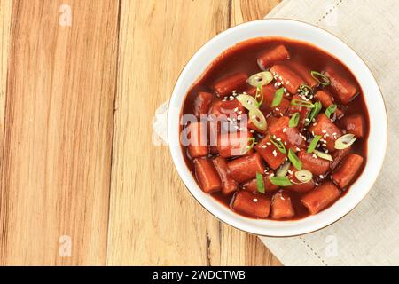 Vue de dessus Stir Fry Spicy Rice Cakes Tteokbokki ou Topokki coréen recouvert de graines de sésame et d'oignon vert, espace de copie pour le texte Banque D'Images