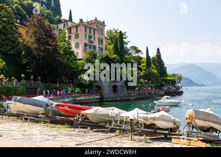 Les touristes bordent la Promenade du Patriarche entre les villas italiennes et le lac de Côme au-delà de la rampe de bateau dans la ville de Varenna, Lombardie, Italie. Banque D'Images