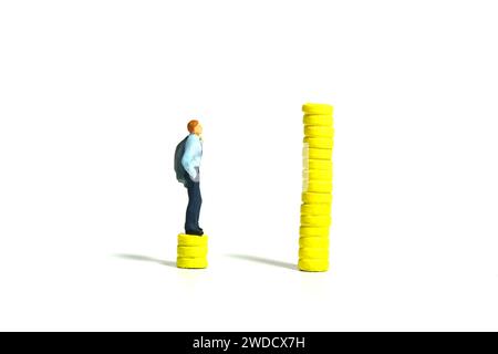 Photographie miniature de figurine de jouet de personnes minuscules. Augmentations de salaire et concept d'écart. Un homme d'affaires debout au-dessus de la pile de monnaie de pièce. Isolé sur un backgr blanc Banque D'Images