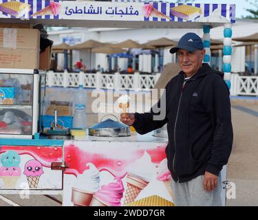 Vendeur de crème glacée mobile tient une crème glacée et sourit à Essaouira, Maroc, le 19 janvier 2024 Banque D'Images