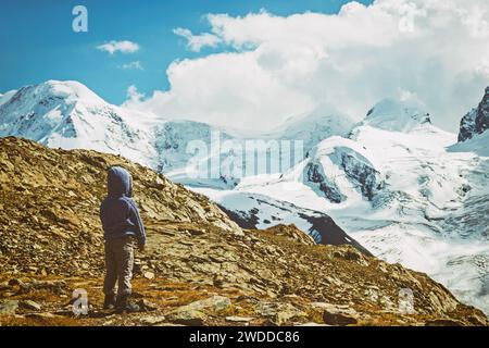 Mignon garçon enfant reposant dans les Alpes, portant veste tricotée chaude et bottes de montagne, image tonique vintage Banque D'Images