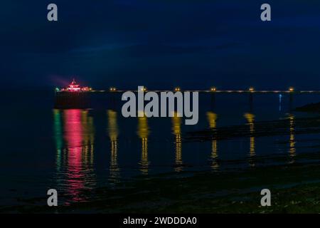 Les lumières colorées sur le Pier se reflètent sur la mer et la boue Banque D'Images