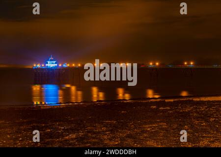 Les lumières colorées sur le Pier se reflètent sur la mer et la boue Banque D'Images