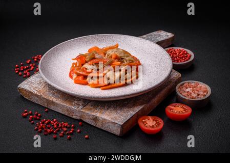 Délicieux ragoût frais avec du poulet ou de la dinde avec des tranches de poivron doux et des carottes avec du sel et des épices sur un fond de béton foncé Banque D'Images