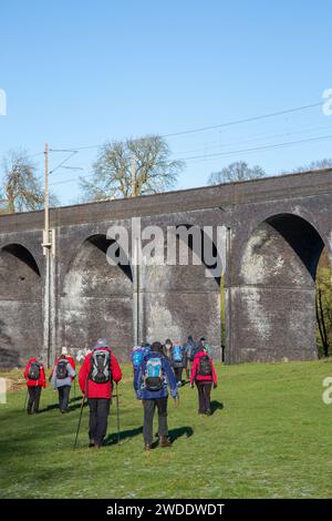 Groupe de randonneurs marchant dans la campagne du Cheshire approchant du viaduc ferroviaire sur la rivière Dean près de Wilmslow Cheshire Banque D'Images