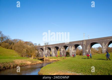 Groupe de randonneurs dans la campagne du Cheshire marchant le long de la rivière Dean approchant du viaduc de chemin de fer près de Wilmslow Cheshire Banque D'Images