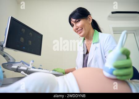 Gynécologue souriant faisant l'échographie d'une femme enceinte cultivée Banque D'Images