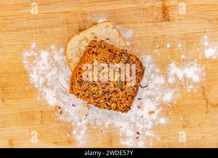Rouleaux de céréales allemands cuits maison frais de la boulangerie arrangés avec de la farine sur une planche de bois photographiés directement d'en haut Banque D'Images