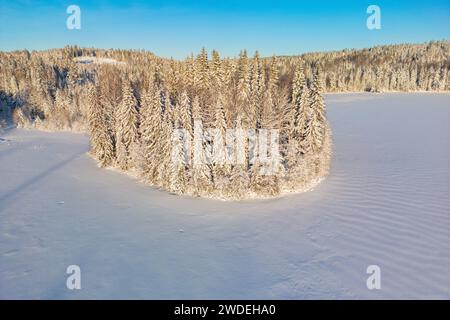 Vue aérienne d'un coucher de soleil doré sur la forêt enneigée hivernale. Vue aérienne drone d'un paysage hivernal. Beau ciel de coucher de soleil sur le lac gelé. Banque D'Images