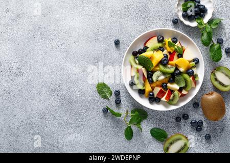 Salade de fruits et baies avec mangue, kiwi, pomme, myrtille et feuilles de menthe fraîche. Alimentation saine, alimentation. Vue de dessus Banque D'Images