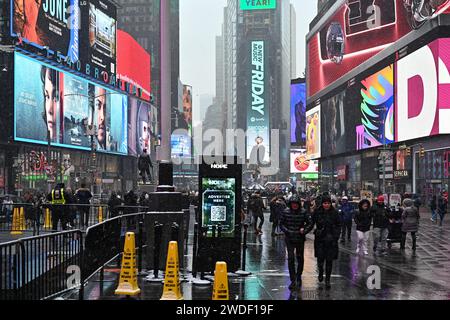 Les gens marchent à travers Times Square alors que la neige tombe pendant une tempête hivernale le 19 janvier 2024. À New York. Banque D'Images