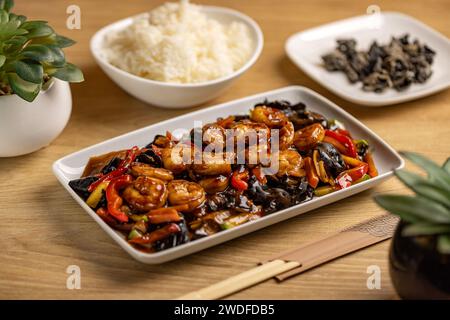 Concept de nourriture épicée thaïlandaise. Crevettes croustillantes sautées avec légumes et champignons dans une assiette blanche. Banque D'Images