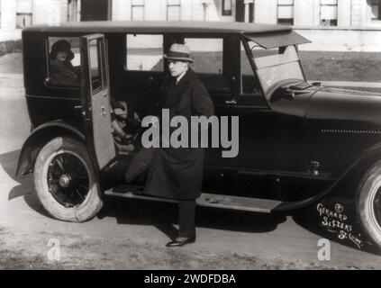Acteur Rudolph Valentino, 1895-1926, portrait en pied, debout en voiture, en manteau astrakhan, 1923 Banque D'Images