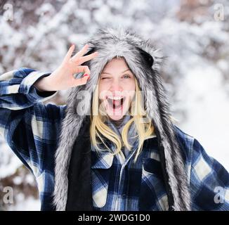 Femme souriante en tenue chaude montrant le signe ok. Fille clignant dans le manteau à carreaux et chapeau de fourrure drôle avec geste d'approbation. Portrait en gros plan de beaux jeunes Banque D'Images