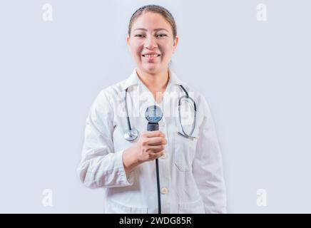 Jeune femme médecin tenant le tensiomètre sur fond isolé. Médecin souriant montrant un moniteur de pression artérielle isolé Banque D'Images