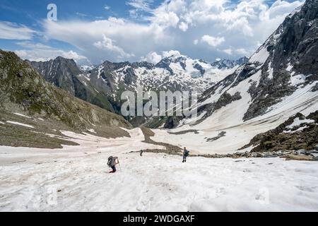 Mountaineers hiking in a snowfield, Noerdliche Moerchnerscharte, behind mountain peak Kleiner Moerchner and Greizer Spitze with snow, Berliner Stock Photo