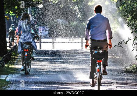 Un cycliste se rafraîchit avec un arroseur de pelouse dans le Tiergarten de Berlin, 03/08/2022 Banque D'Images