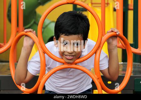 Un garçon latino-américain de 9 ans à la peau foncée joue dans un terrain de jeu comme une activité physique vivant dans la pauvreté comme thérapie pour le TDAH Banque D'Images