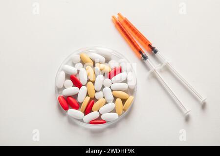 Diverses pilules colorées dans la boîte de Petri isolé sur blanc, vue de dessus. Assistance médicale. Laboratoire de pharmacie et concept de recherche pharmaceutique. Banque D'Images