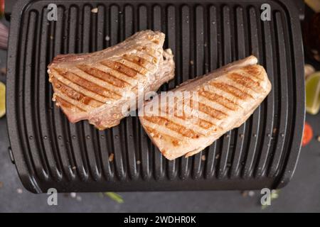 Deux morceaux grillés de filet de thon sur un grill électrique à la cuisine domestique Banque D'Images