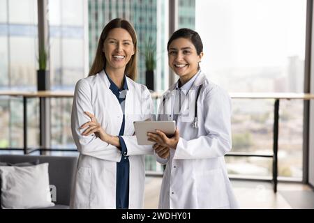 Deux belles femmes médecins en blouses uniformes blanches posant ensemble Banque D'Images