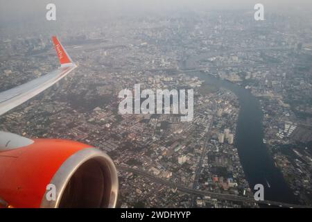 Bangkok, Thaïlande. 15 janvier 2024. Une vue aérienne de Bangkok depuis une fenêtre d'avion qui vient de décoller de l'aéroport Don Mueang, avec le logo sur l'aile de l'avion de la compagnie Firefly Airlines. L'aéroport international Don Mueang est l'un des deux aéroports internationaux desservant la région métropolitaine de Bangkok. Crédit : SOPA Images Limited/Alamy Live News Banque D'Images