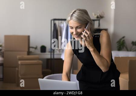 Femme parlant sur smartphone, commandant la compagnie de transport, travaillant dans l'entrepôt Banque D'Images