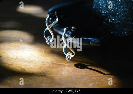Statuette noire d'une main féminine mate avec boucles d'oreilles en argent avec de belles pierres et un pendentif. Banque D'Images
