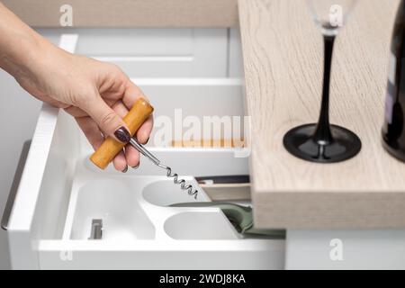 femme tient un tire-bouchon dans sa main pour ouvrir une bouteille de vin, faible profondeur de champ. alcoolisme féminin. Banque D'Images