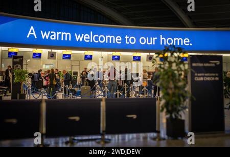 Les passagers font la queue pour s'enregistrer en classe affaires British Airways sous un grand panneau lumineux indiquant « Un accueil chaleureux à notre domicile » London Heathrow Air Banque D'Images